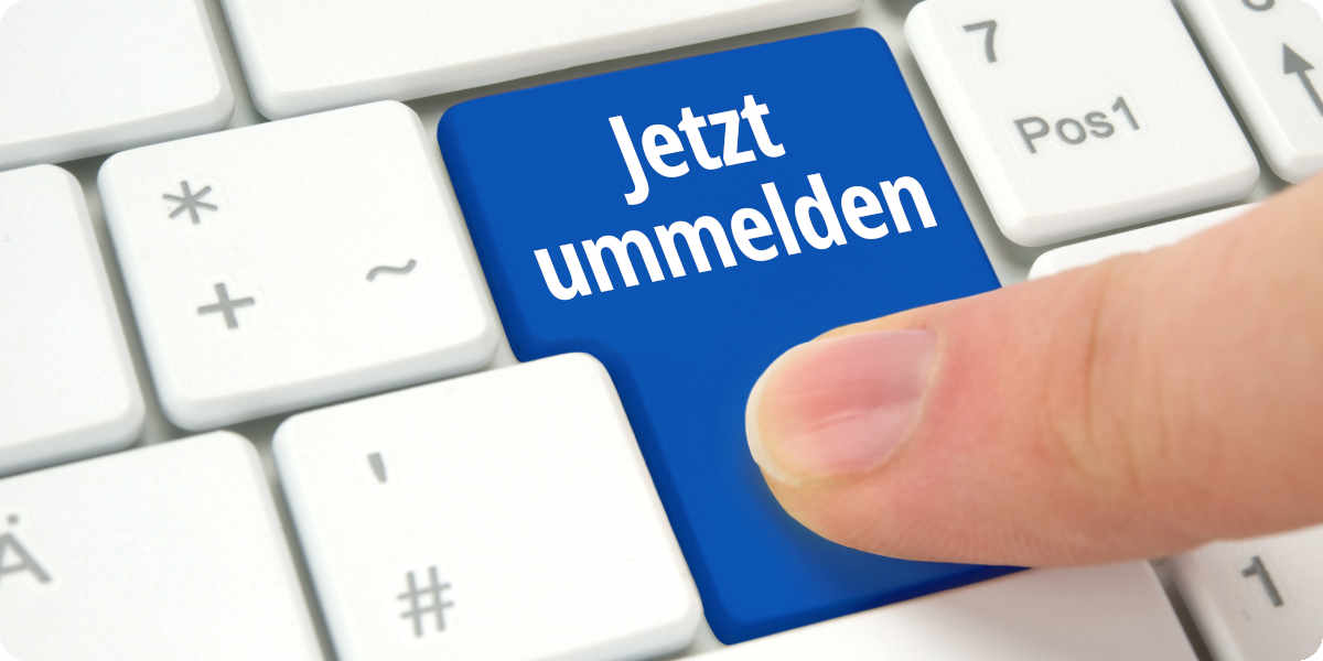 Ein Finger tippt auf eine blaue Taste mit der Aufschrft "jetzt ummelden" einer Tastatur.
