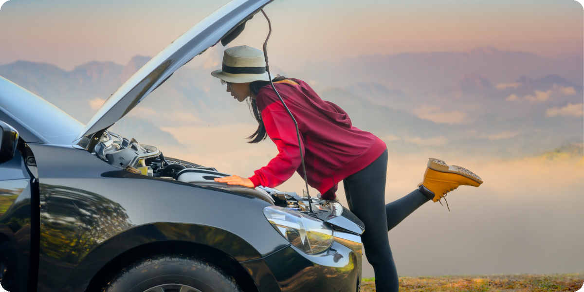 Eine Frau steht vor dem Auto und schaut in den Motorraum.