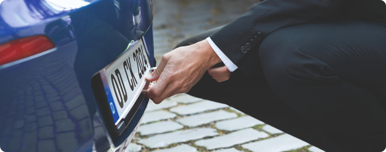 Eine Person baut das hintere Kennzeichen des Autos f&uuml;r die Abmeldung ab.