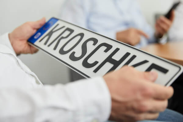 Ein Mann h&auml;lt Carbonkennzeichen in der Hand.