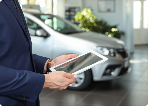 Ein Automobilverk&auml;ufer h&auml;lt im Autohaus ein Tablet in der Hand.